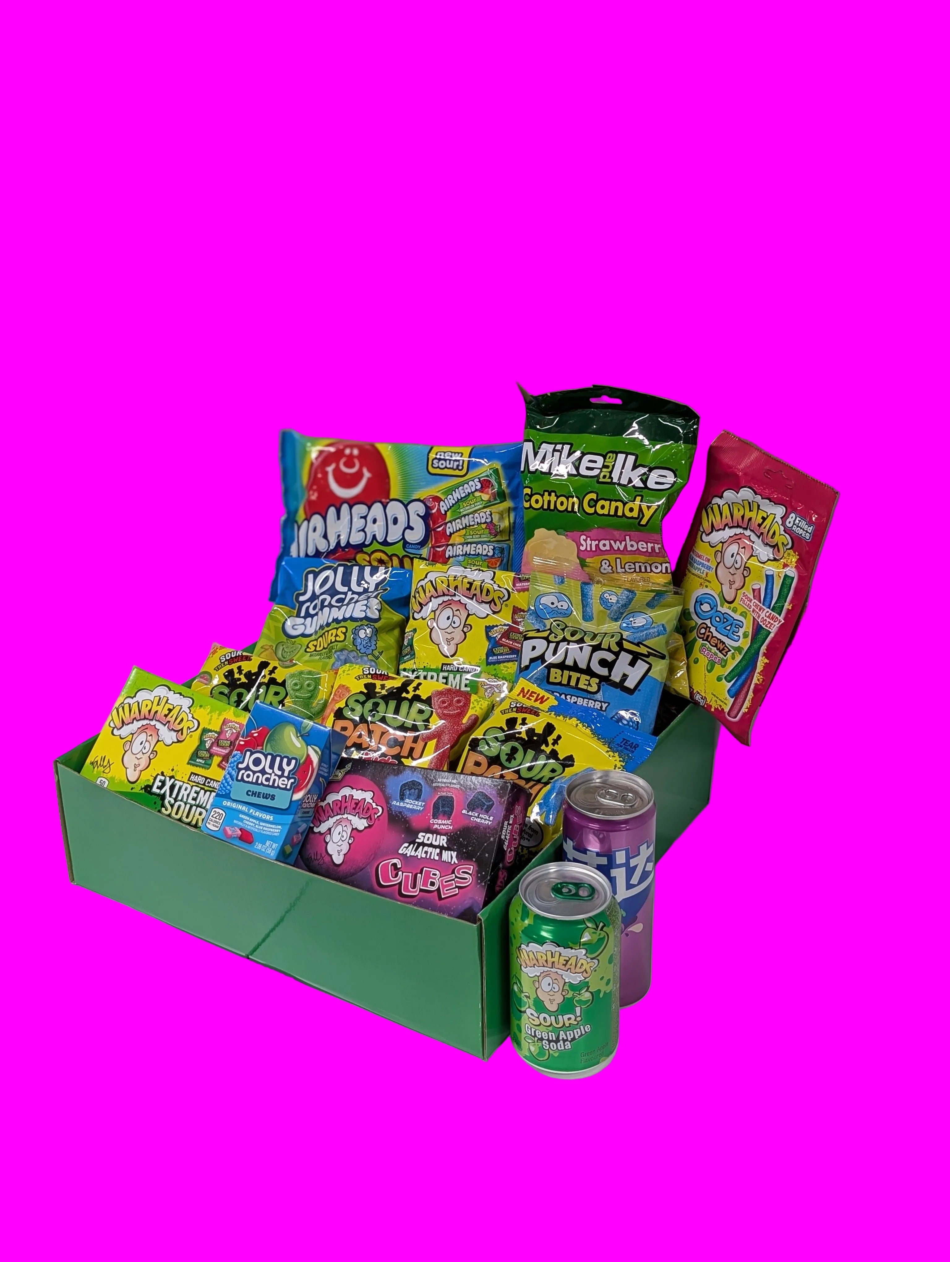 Assorted candy and soda cans in a green box on a white floor.